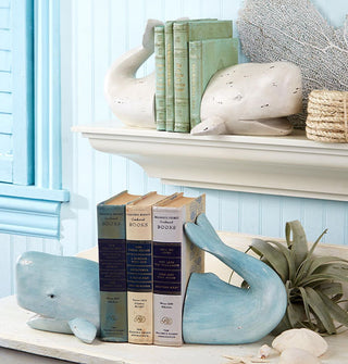 White and blue whale bookend sets are staged on shelves with other coastal decor against a backdrop of blue wainscoting