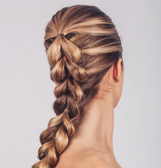 Model wears a thick fishtail French braid secured by small nearly invisible elastics
