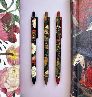 Three floral patterned click-top ballpoint pens between two floral patterned journals