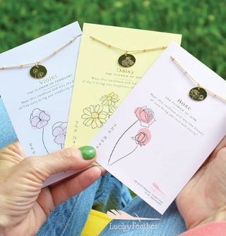 Model holds three fanned out flower necklace cards: Violet, Daisy, and Rose