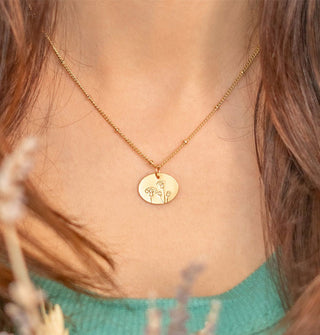 Model wears a flower-etched oval pendant necklace on gold satellite chain