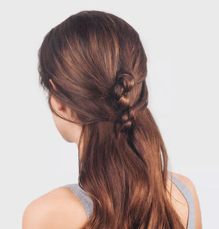Model wears a two-tiered twist in a partially swept-back hairstyle