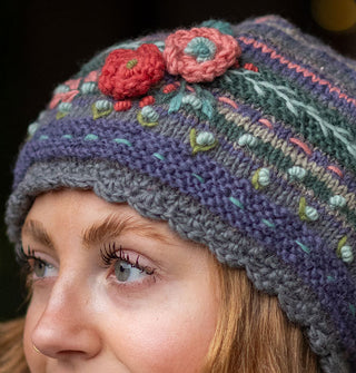 Model wears a colorful knit beanie with textural floral, vine, and polka dot embroidery