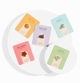 Assortment of polished, carved stones representing Bliss, Peace, Drift, Bloom, and Wild symbolism, each attached to a colorful printed card