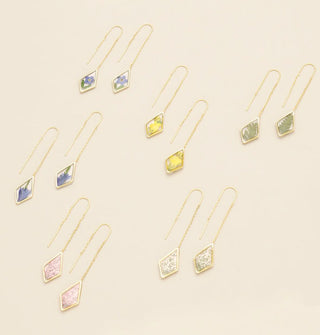 Collection of gold threader earring pairs, each with a diamond-shaped accent with resin-encased pressed flowers of different kinds