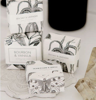Grouping of four bar soaps wrapped in packaging with black and white natural and botanical designs