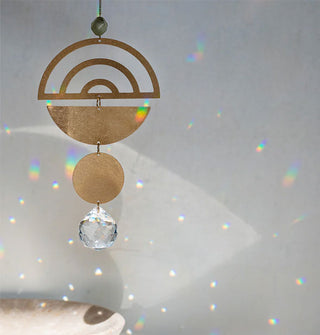 A brass and crystal suncatcher throws rainbows onto the wall behind it