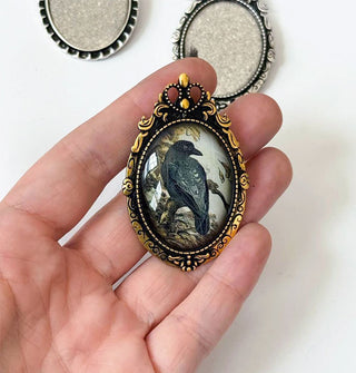 Model's hand holds a gold-framed crow brooch