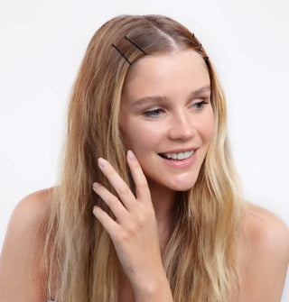 Smiling model lightly touching hair lengths wears several black bobby pins near temples