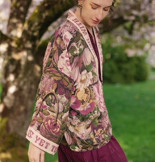 Model wears a cropped robe with lush pink and purple floral print and contrasting text banner trim