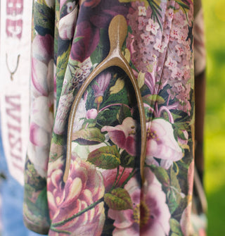 Closeup of a wishbone design among pink and purple florals with greenery on a silken robe