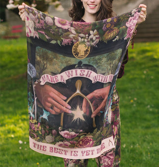 Smiling model holds a large silken scarf with wishbone and floral motif