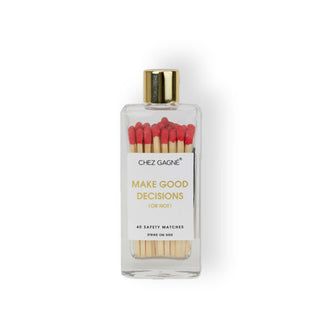 Clear rectangular glass bottle with gold cap and a label that says, “Make good decisions” in gold lettering contains red-tipped wooden matchsticks