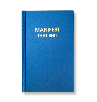 Metallic blue hardcover journal says, "Manifest That Shit" in gold foil lettering