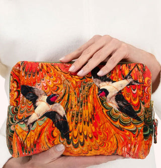 Model holds a quilted orange velvet swallows pouch