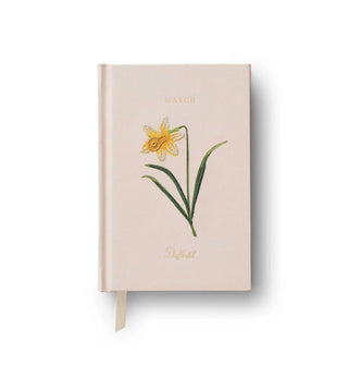 Cream-colored notebook hardcover with yellow daffodil embroidery says, "Daffodil" at bottom in gold script and "March" at the top in gold print