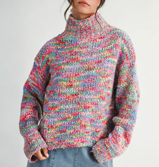 Model wears a multicolored, oversized  turtleneck sweater