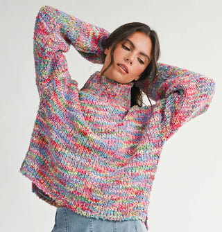 Model with arms upraised wears a multicolored, oversized  turtleneck sweater