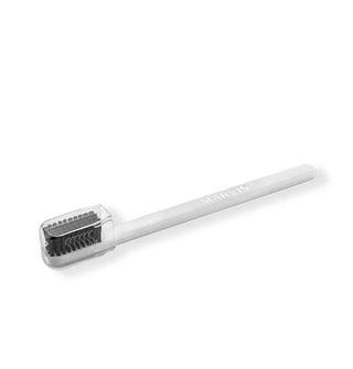 White toothbrush with black bristles under a clear acrylic cover