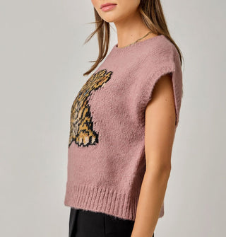 Model wears a dusty pink sweater vest with blue-eyed leopard cub graphic and ribbed hems