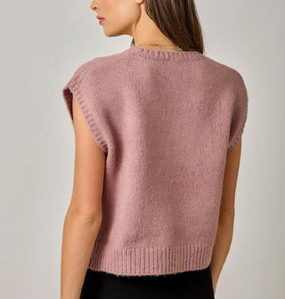 Model with back to camera wears a dusty pink sweater vest