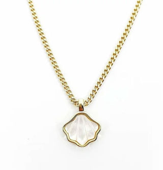 A white mother of pearl seashell charm set in gold hangs on a thin gold curb chain