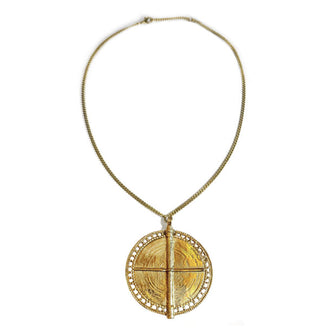 Large round gold-toned medallion with lacy edge and central "t" or cross formed by two perpendicular ridges is attached to a thin curb chain with extender