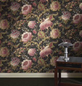 Bold floral wallpaper on a wall above white molding with a small table and lamp in front