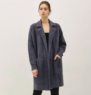 Model wears a long, dark muted blue fuzzy coat/cardigan with notched collar and pockets