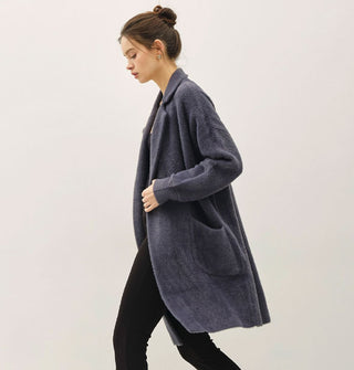 Model wears a long, dark muted blue fuzzy coat/cardigan with notched collar and pocket
