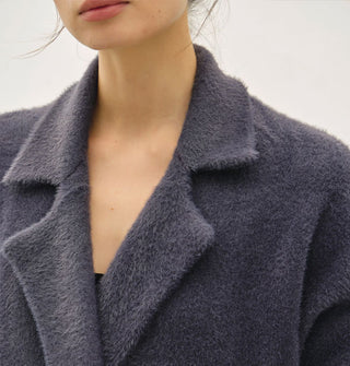 Model wears a dark muted blue fuzzy coat/cardigan with notched collar