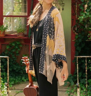 Model holding an ukulele wears a hip-length kimono-style cardigan with sunflower motif and contrasting black and white borders
