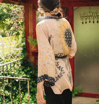 Model facing away from the camera wears a kimono-style cardigan with contrasting black and white print borders and matching belt