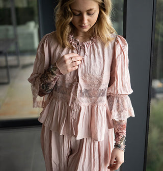 Model wears a two-piece set of lace-trimmed tie-front blouse and loose-fitting pantaloons