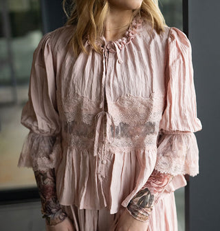 Model wears a lace-trimmed tie-front blouse with ruffle neck and puffy elasticated sleeves