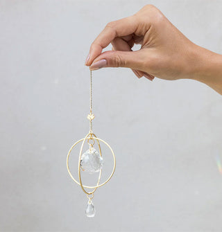 Model's hand holds a double-circle crystal suncatcher with lotus charm