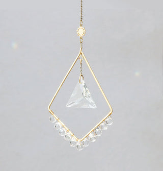 Gold upside-down diamond-shaped ornament on gold chain with small sun charm at top and triangular crystal hanging in the middle with smaller circular crystals hanging from the bottom two sides