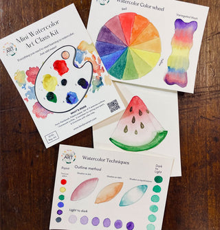 Contents of the Mini Watercolor Art Class Kit on a wooden tabletop