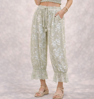 Model wears light green pantaloons with flocked velvet floral pattern, elasticated tie waist, and lace trim