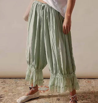 Model wears a pair of sage green lace-trimmed bloomers with ballet flats