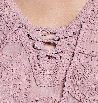 Closeup of a lace-up neckline on a heavily crocheted pink blouse