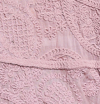 Closeup of intricate crochet work on a sheer pink blouse