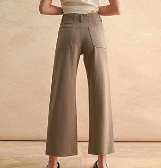 Model wears a pair of cropped flared tan pants with pockets and belt loops