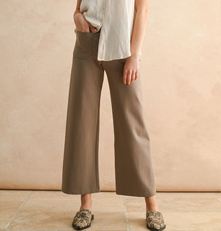 Model wears a pair of cropped flared tan pants with a white shirt and leopard print mules