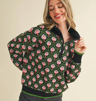 Smiling model wears a green, black, and pink floral print pullover with half zipper, mock neckline, and knit hem and cuff bands