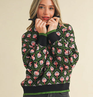 Model wears a green, black, and pink floral print pullover with half zipper, mock neckline, and knit hem and cuff bands