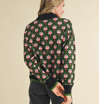 Smiling model wears a green, black, and pink floral print pullover with mock neckline, and knit hem and cuff bands