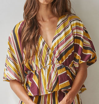 Model wears a brown, burgundy, rose, gold, and white striped V-neck top with gathered waist and puff elbow-length sleeves