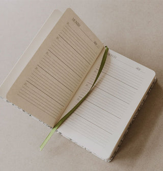 An opened Mom's One Line a Day Journal shows five-year lined spaces to write and an attached green ribbon bookmark