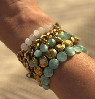Model's wrist is fitted with an assortment of five brass and stone bracelets